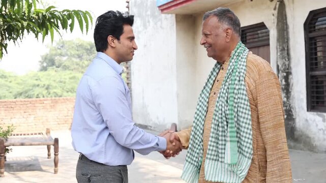 Young indian bank manager or financial adviser shaking hands with a farmer. Rural india.