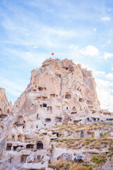 A striking vertical photograph of Uchisar Castle in Cappadocia, Turkey, showcasing ancient cave dwellings carved into dramatic beige rock formations