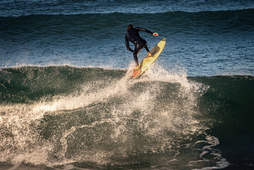 A surfer wearing a wetsuit launching off the lip of a wave