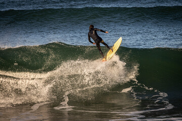 A surfer wearing a wetsuit launching off the lip of a wave