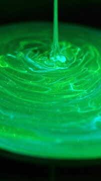 Extreme close up slow motion liquid pooling and expanding with a shimmering vibrant green and turquoise internal glow creating organic abstract shapes science, artistic, pooling