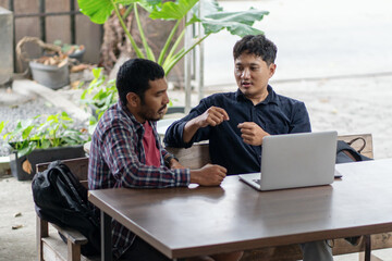 Two men working together in an outdoor cafe space