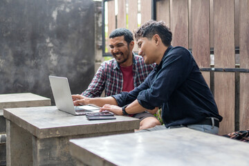 Two men working together in an outdoor cafe space