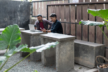 Two men working together in an outdoor cafe space