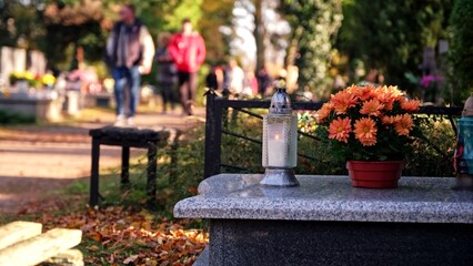 Anonymous People Walking Down Cemetery Alley by Tombstone Graves Decorated with Votive Candle Lanterns on All Saint Day