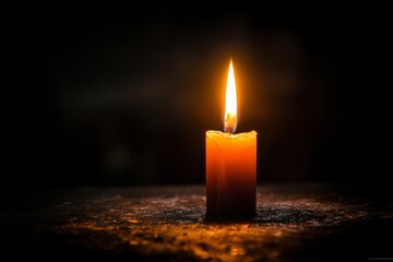 Single glowing candle flame illuminating darkness with warm, comforting light.