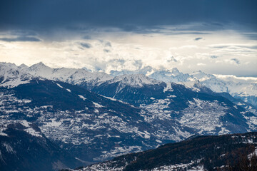 Panorama hivernal des Alpes avec cha&icirc;ne de montagnes enneig&eacute;es. Ciel nuageux dramatique, ambiance froide et montagneuse.