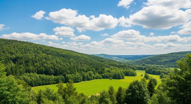Scenic Valley of Lush Greenery: A panoramic vista of rolling hills blankets in verdant trees, under a cloud-strewn azure canvas. Capturing the tranquility of nature's embrace.