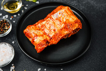 Spicy pork ribs on black plate with rosemary and salt