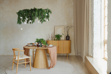Dining table set with greenery above in a bright, minimalist room with natural light