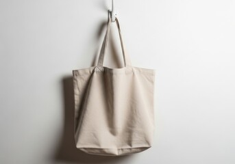 Beige canvas tote bag hanging on a hook against a white wall