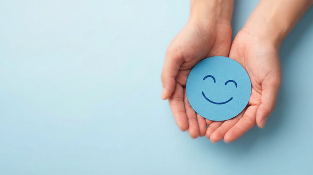 Hands gently holding a blue circular card with a smiling face, symbolizing positivity and emotional well-being in a serene environment