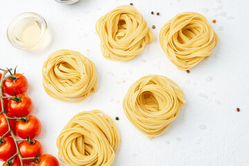 Closeup of raw pasta nests with pepper and salt on white background