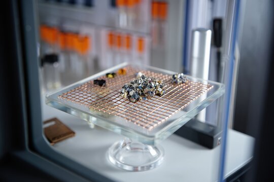 Nanomaterials showcased on a glass pedestal beneath a controlled electron microscope.