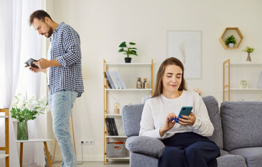 Social media addiction of couple at home, suspicions of infidelity and cheating in relationship. Two busy people check digital devices, woman typing on smartphone, man using tablet to read text