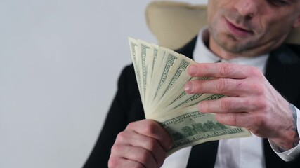 A man or businessman spreads money out in a fan and rejoices in his earnings and success