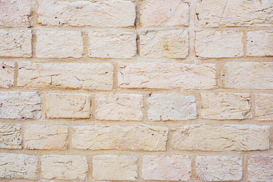 Textured beige brick wall surface with weathered look and visible mortar
