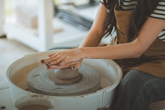 Woman shaping clay on pottery wheel in creative workshop, hands working with wet clay to craft handmade ceramic art, artistic lifestyle, pottery class, craft process, DIY ceramic making in studio