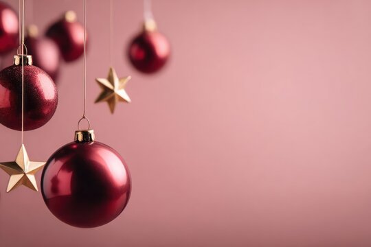 Festive hanging deep red christmas ornaments and golden stars adorn a soft pink background with copy space