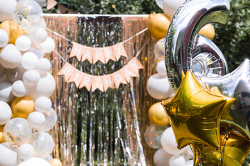 Birthday decorations - balloons, a number 6, and a garland for a children's party. A "Happy Birthday" sign on a photo area made of foil rain, a festive location.