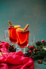 Two glasses of red winter drink with orange slices cinnamon sticks and anise seeds