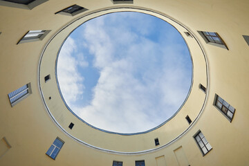 Fototapeta premium A round courtyard of a house with a view upwards to a blue sky with clouds