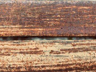 close-up view of two horizontal bands of heavily rusted metal, separated by a narrow gap