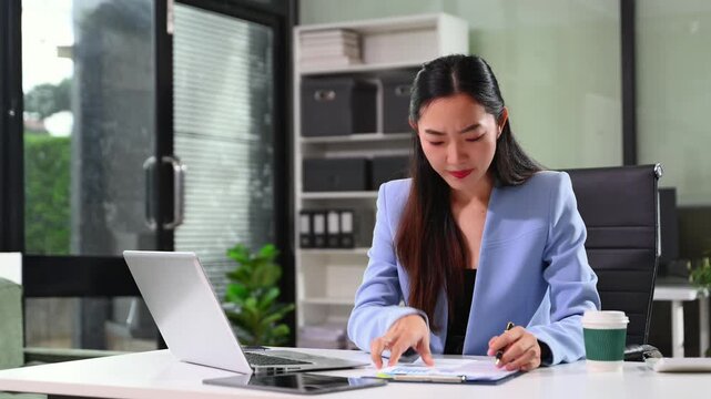 Frustrated young businesswoman working on a laptop computer sitting at his working place in office