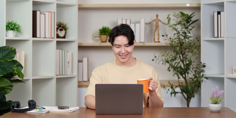 Work from Home: Young man enjoying coffee while working on laptop