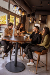 Group of friends sitting at a bar table in a café and having fun