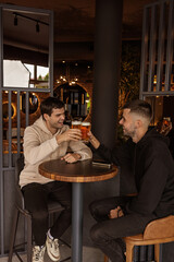 Two  friends are toasting with beer in a cafe