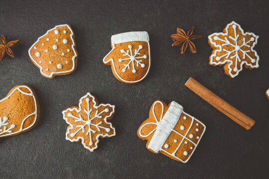 Sweet Christmas cookies shaped like trees mittens snowflakes and gifts with cinnamon sticks