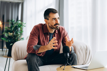 Male podcaster recording conversation discussing topics at home studio