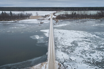 Aerial view of a wooden bridge over a freezing river with ice
