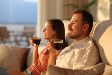 Happy couple smelling coffee aroma at home at sunset