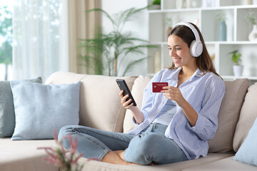 Happy woman in blue wearing headphone buying online