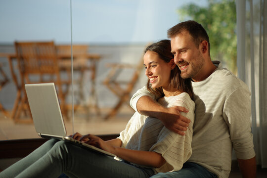 Happy couple in love using laptop in a house indoor