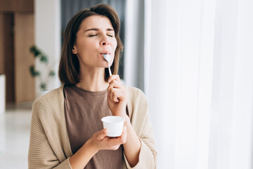 Woman enjoying healthy yogurt snack with pleasure