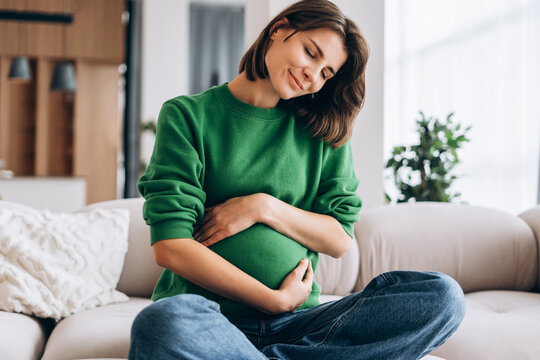 Pregnant woman embracing baby bump with tenderness and happiness - Powered by Adobe