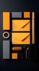 Organized flat lay of office and decorative items in orange, grey and wood tones on a dark background