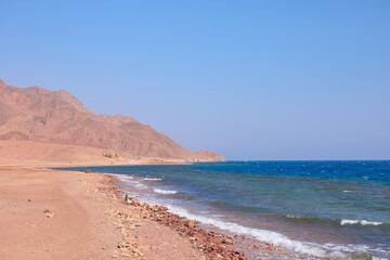 Serene coastal landscape with sandy beach and gentle waves under clear blue sky