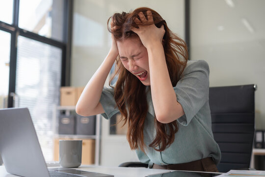 Stress businesswoman is sitting at table, under stress from working.