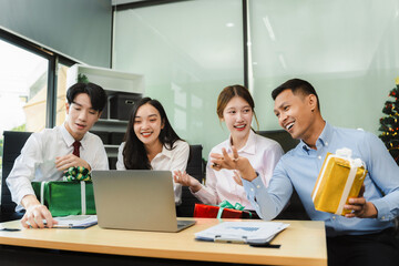Asian people, celebrating together and gift exchange at Merry Christmas & Happy New Year. excited businessman feel happy work complete and celebration successful deal.