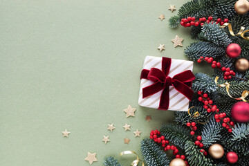 Golden gift or present box with velvet red ribbon with festive decoration on green background for...