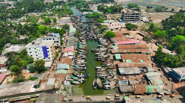 Aerial view of a bustling river market in a densely populated tropical town with many boats docked along the waterway Teknaf, Cox's Bazar, Bangladesh