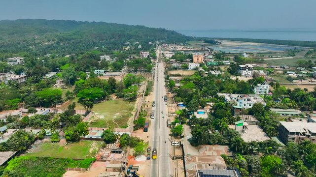Aerial view of a coastal town road lined with buildings and lush green trees under a bright sky Teknaf, Coxsbazar, Bangladesh