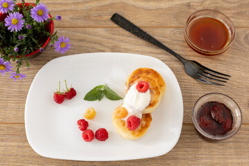 Curd fritters with sour cream, raspberries, strawberry jam and honey.