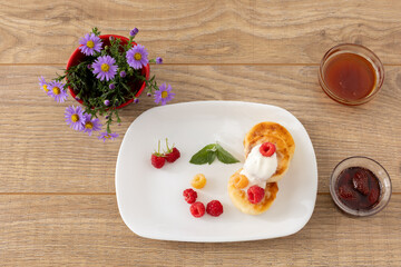 Curd fritters with sour cream, raspberries, strawberry jam and honey.