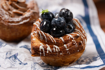 Golden pastry topped with glossy blueberries and icing.