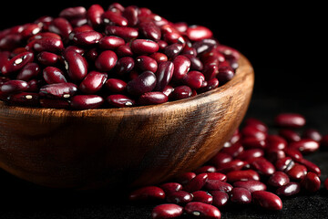 Red beans in a wooden bowl on a black background